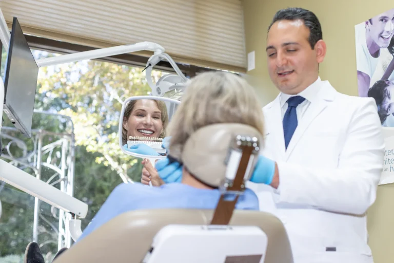 Patient smiling into a hand mirror with Dr. Ben at the chair