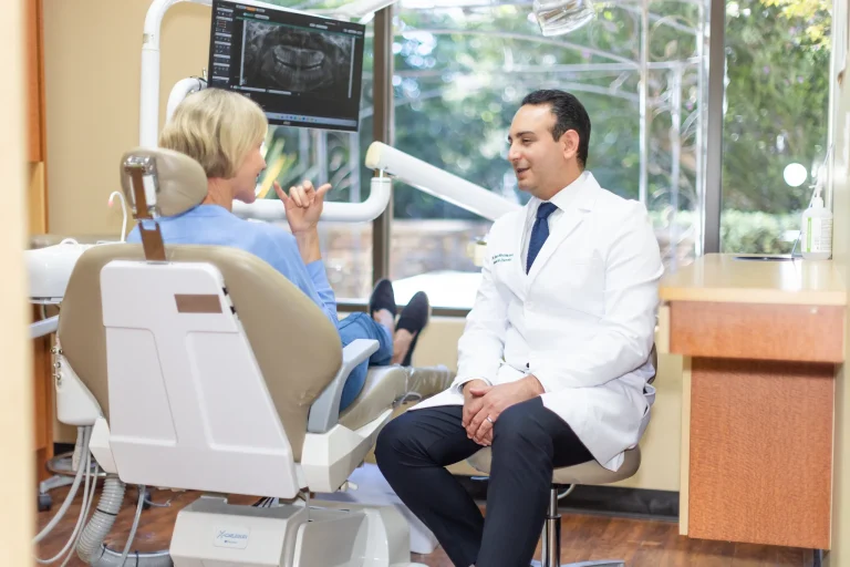 Dr. Ben seated in conversation with a patient in the operatory