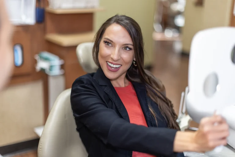 Patient holding a hand mirror and smiling in the chair