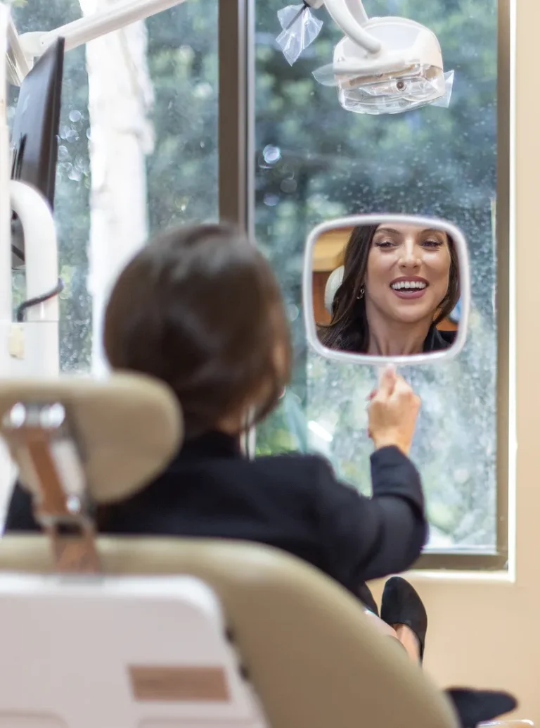 Patient holding up a mirror to look at her smile